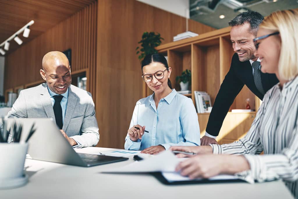 Group of businesspeople laughing while going over paperwork